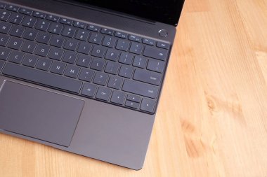 Klavye, touchpad ve bej ahşap masa yüzey üstten görünüm portre siyah açılan laptop ekranının boş ayna ile açılan laptop parçası