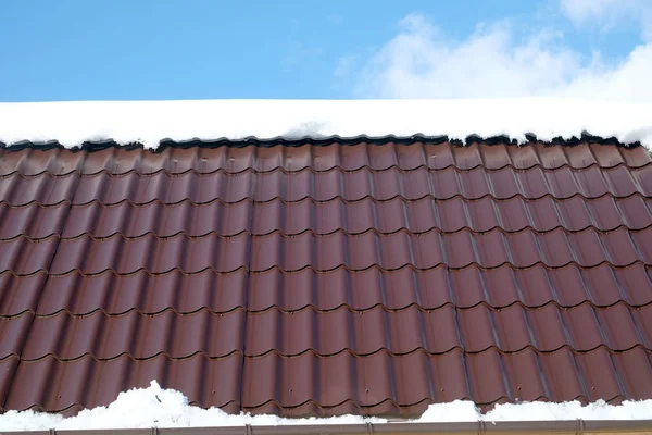 青い空に白い雲が正面の下で晴れた春の日に雪を茶色の金属瓦から国の家の屋根の側 — ストック写真