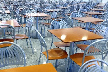 Birçok kahverengi kare masa ve metal sandalye boş kafe salonu yüksek modern binanın içinde kalan yemek
