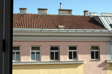 Parlak güneşli bir günde pencerenin karşısındaki evin üst kısmını görüntüle