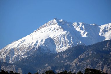Zirvesinde kablo terminali olan Kemer yakınlarındaki temiz beyaz karlı Tahtali dağının önü manzaralı. Tahtali, Antalya bölgesindeki en yüksek Türk dağıdır.