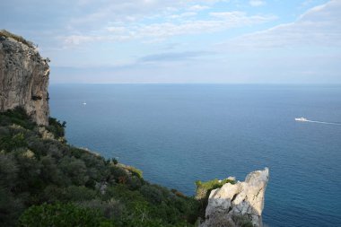 High impregnable plateau with mountain vegetation on top and slopes and calm sea far and down on skyline on sunny day view