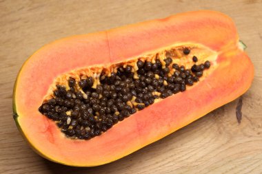 Yarısı kesilmiş olgun, lezzetli papaya meyvesi sulu portakal hamurlu stüdyo fotoğrafı ahşap arka planda yakın plan görüntüsü