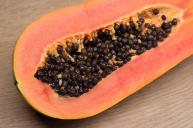 Yarısı kesilmiş olgun, lezzetli papaya meyvesi sulu portakal hamurlu stüdyo fotoğrafı ahşap arka planda yakın plan görüntüsü