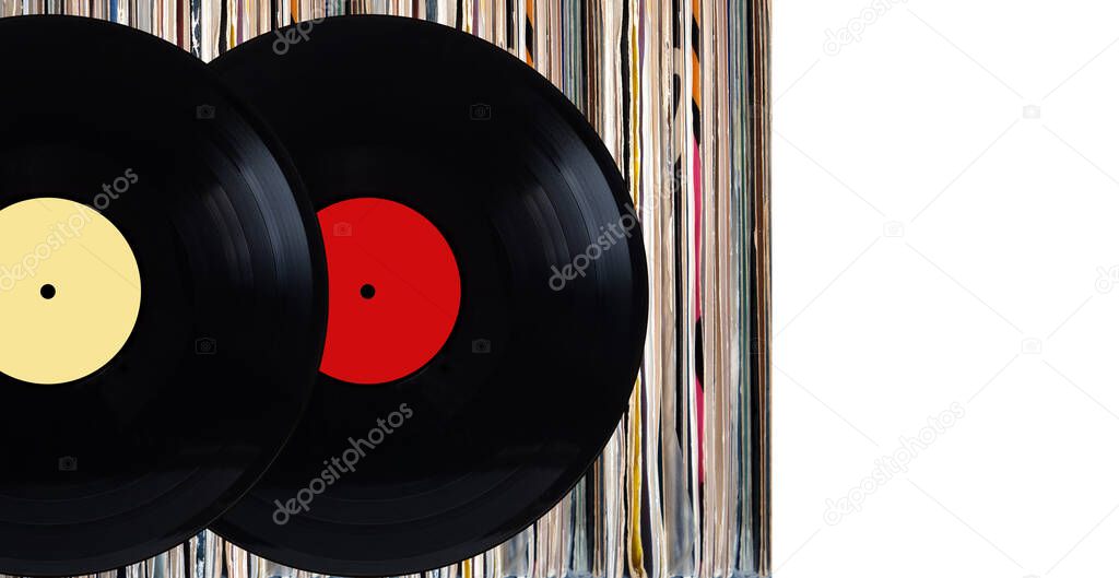 Two black vinyl records with color labels in front of shelf of many close standing vinyl discs in old color covers over white background studio photo front view closeup