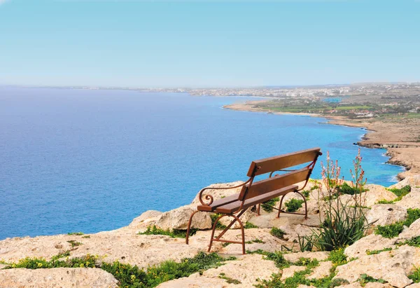 Panca in legno sulla roccia con vista mare Immagine Stock