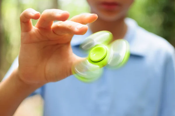 Jongen spelen met een Tri Fidget Hand Spinner Rechtenvrije Stockfoto's