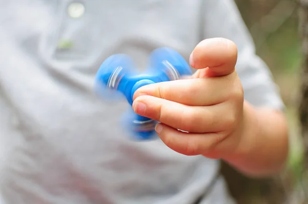 Junge spielt mit einem Tri-Fidget-Handspinner Stockbild