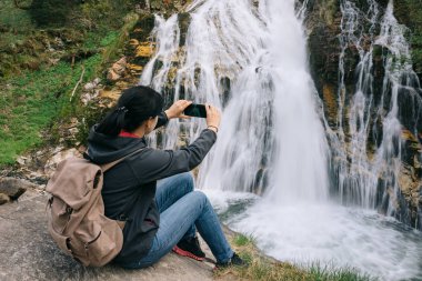 Bir kız bir şelale bir cep telefonu kamera resim çekme