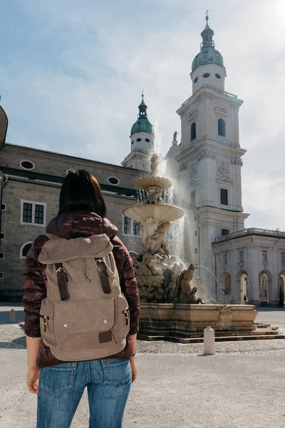 Chica viajero con una mochila cerca de la fuente y la catedral — Foto de Stock