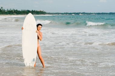 Sörf tahtası ile sahilde duran genç bayan sörfçü. Sri Lanka. Hikkaduwa