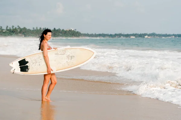 Young lady surfer standing on the beach with surf board. Sri Lanka. Hikkaduwa. — Stock Photo, Image