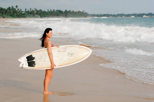 Young lady walking with surf board on sandy tropical beach. Sri Lanka. Hikkaduwa. — Stock Photo, Image