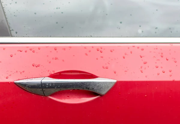 Gouttelettes d'eau sur la poignée d'une voiture rouge . — Photo