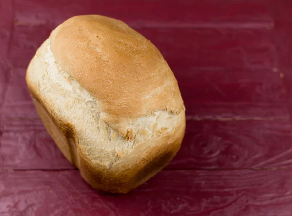 Ένα καρβέλι ψωμί σπιτικό λευκό σε σκούρο κόκκινο φόντο ξύλινη. — Φωτογραφία Αρχείου