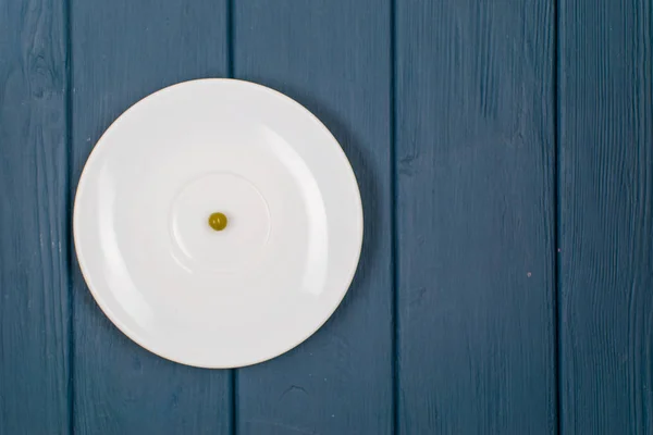 Het concept van honger, boulimie. Pea op een witte plaat en vork. — Stockfoto