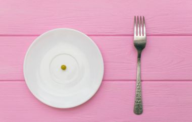 Açlık, kavramı bulimia. Bezelye bir beyaz tabak ve çatal.