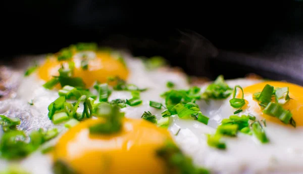 Жареные куриные яйца с зеленым и весенним луком в сковороде . — стоковое фото