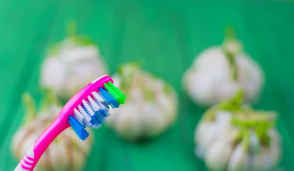 Toothbrush and garlic on a wooden green background. — Stock Photo, Image