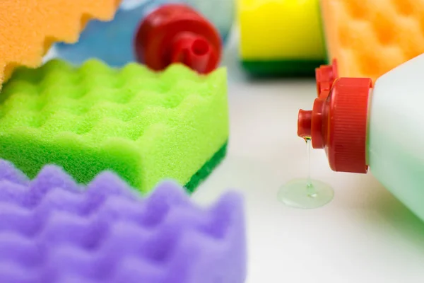 Multicolored foam rubber sponges and detergent on a light background.