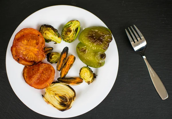 Grilled vegetables on a white plate on a black background. — Stock Photo, Image