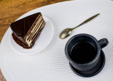 Kahve ve pasta beyaz bir plaka üzerinde bir kil siyah Kupası.