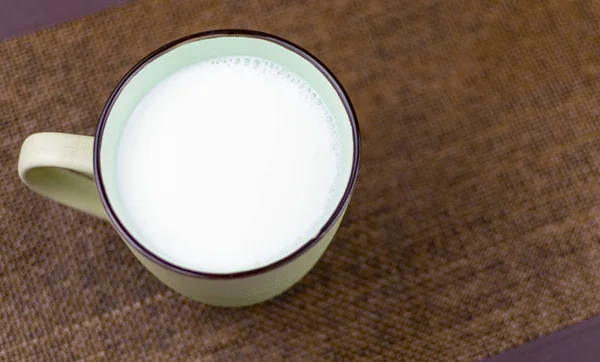 Eine große Tasse Milch auf braunem Hintergrund. — Stockfoto