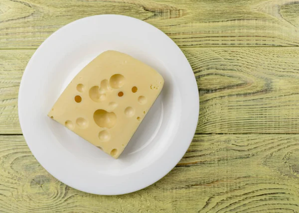 Ein Stück Käse mit Löchern auf einem weißen Teller. — Stockfoto