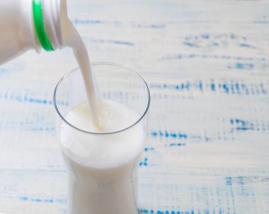 Kefir, ekşi süt ürünü bir ahşap zemin üzerine bir bardak içine dökme.