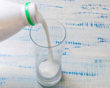Kefir, ekşi süt ürünü bir ahşap zemin üzerine bir bardak içine dökme.