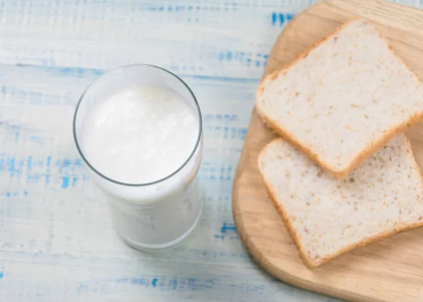 Kefir, jogurt w szklance na tle plasterków białego chleba na drewnianym tle. — Zdjęcie stockowe