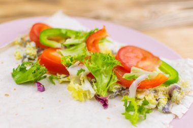 Tahta arka planda bir rulo Pita ekmeği ve taze sebze hazırlamak. Sağlıklı beslenme kavramı.