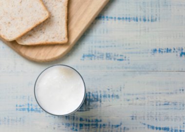 Kefir, arka planda beyaz ekmek dilimlerinin olduğu bir bardakta yoğurt..