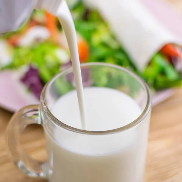Despejando em um kefir de vidro (leite) e legumes frescos. O conceito de alimentação saudável. Vegetarianismo . — Fotografia de Stock