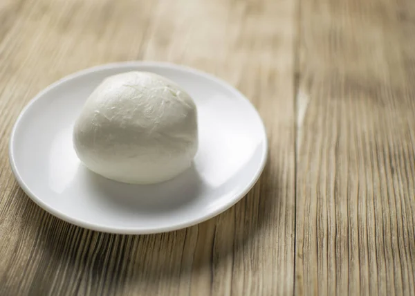 Mozzarella sur une assiette sur un fond en bois . — Photo