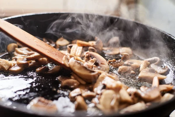 Fried mushrooms in a pan. Cooking mushrooms with steam emanating from them.