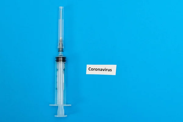 青の背景にコロナウイルスの碑文と医療注射器 — ストック写真