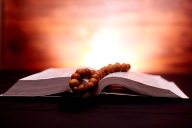 Koyu kahverengi arka planda İncil ve kilise tespihi. İnancın, dindarlığın, duanın sembolü.