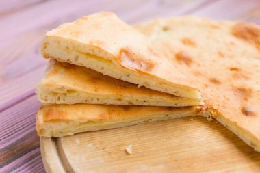 Tahta arka planda peynirli dilimlenmiş turta. Khachapuri.