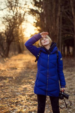 Ormanda kameralı gün batımında bir kadın. Doğa fotoğrafçısı kadın konsepti.