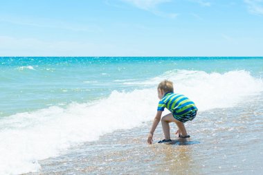 Okyanusta, denizde şapkası olan küçük bir çocuk..