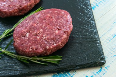 Siyah bir taş yüzeyde iki çiğ kıymalı köfte..