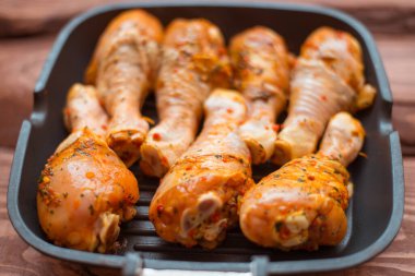 Sos içinde çiğ tavuk budu ve tavada baharat, ahşap arka plan değil..