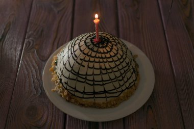 Pastanın üzerinde yanan mum.