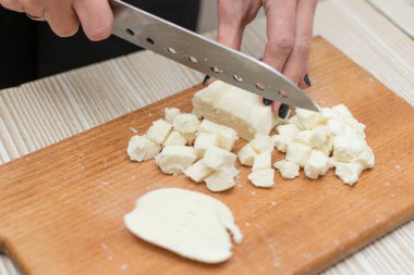 Kadın kesme tahtasıyla peynir dilimliyor..