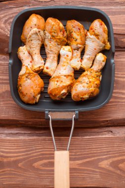 Sos içinde çiğ tavuk budu ve tavada baharat, ahşap arka plan değil..