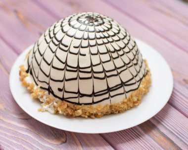 Tahta arka planda küresel çikolata serpiştirilmiş kremalı pasta..