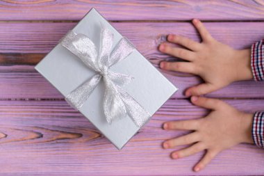 Hediye kutusu ve tahta arka planda çocuk elleri..