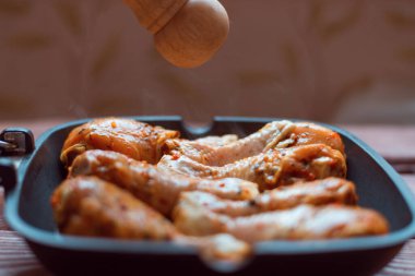 Sos içinde çiğ tavuk budu ve tavada baharat, ahşap arka plan değil..