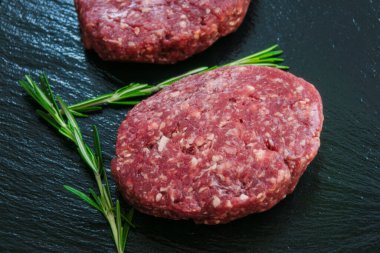 Siyah bir taş yüzeyde iki çiğ kıymalı köfte..